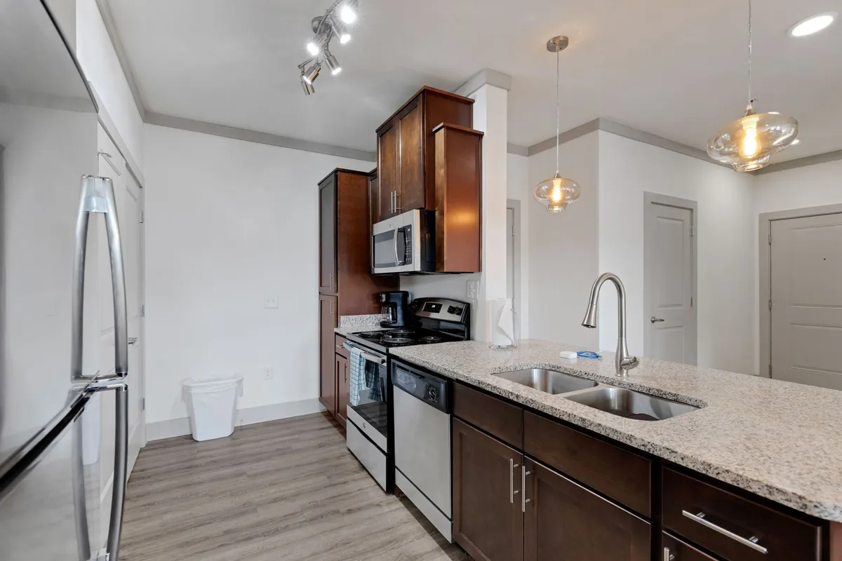 This scene highlights a spacious kitchen boasting a granite countertop, stainless steel appliances, and a kitchen island. The area is bright and organized, ideal for preparing meals or hosting gatherings. The setup demonstrates the utility of a well-equipped kitchen for both families and business travelers.